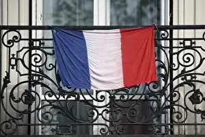 A French flag hangs from a balcony in Paris to pay tribute to the victims of the Paris