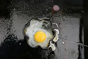 Food And Drink Prints: A fried egg is seen on a grill in a roadside snack cafe along the A49 near Tittensor