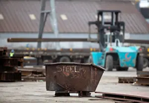 Prints of A garbage bin with the words STEEL MY JOB! painted on it sits in a storage yard where structural steel is loaded onto a truck in the portlands of Hamilton, Ontario, Canada, March 9, 2018 USA Prints: A garbage bin with the words STEEL MY JOB! painted on it sits in a storage yard where