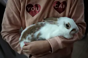 A girl holds a rabbit after being blessed by a priest outside San Anton Church in