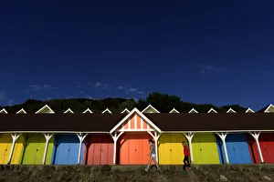 United Kingdom Prints: Two girls walk past beach huts in the North Bay in Scarborough
