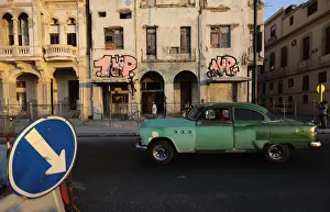 Two graffiti artists paint on a building on Havanas seafront boulevard El Malecon