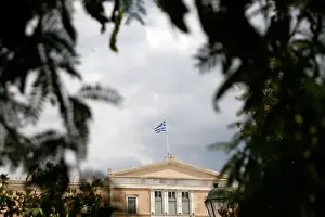 A Greek flag flutters atop the parliament building in Athens
