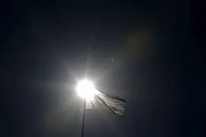 A Greek national flag flutters atop the parliament building in Athens