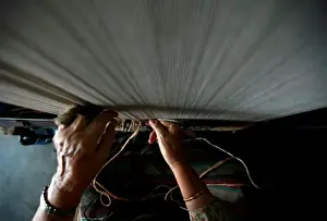 A hand of a Tibetan refugee is pictured as she works to weave a traditional carpet