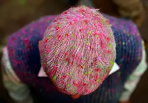Festival Prints: A Hindu devotee is covered in coloured powder as he stands outside a temple during