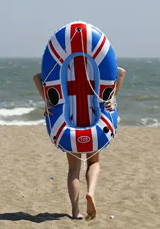 Holiday-maker walks towards the sea with her inflatable boat during heatwave in Skegness