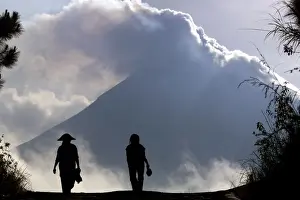 Indonesian farmers are silhouetted in front of Mount Merapi at Srumbung village, near