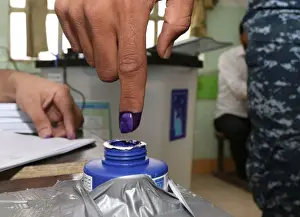 An Iraqi security member dips his finger in ink after casting his vote at a polling