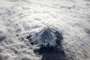 Japan Prints: Japans Mount Fuji, covered with snow and surrounded by cloud, is seen from an airplane
