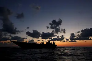 Migrant Prints: Libyan migrants on a wooden boat await rescue by the migrant search