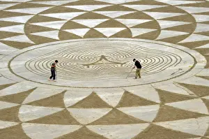 Local artists draw patterns in the sand at low tide on North Beach, Tenby, South Wales