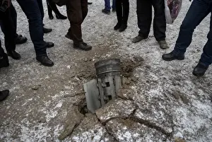 Local residents look at the remains of a rocket shell on a street in the town of