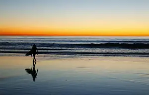 A lone surfer heads home after surfing past sunset in Leucadia
