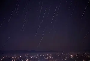 A long exposure picture shows a star trail above the mountain range during the Geminids