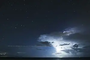 Mexico Prints: A long exposure shot shows a plane flying over the sea during a lightning storm on