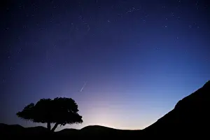A long exposure shows a meteor streaking across the sky in the early morning during