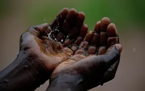 A Malawian child catches raindrops during a brief downpour in Ngozi village near