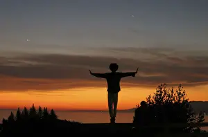 A man balances on a fence post as he watches the sun set over the Pacific Ocean in Santa Monica