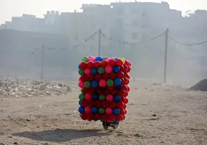 India Prints: A man carries childrens coloured plastic balls on his motorcycle in Delhi