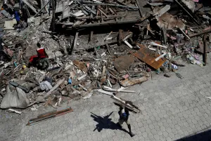 Storm Prints: A man carries wooden planks salvaged from the rubble of a destroyed houses after