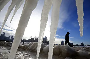 Weather Prints: Man is framed by icicles as he walks along a beach in Chicago