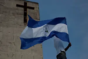 A man holds up a Nicaraguan flag during a protest march to demand an end to violence in