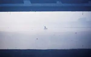 India Prints: A man paddles a handmade boat across the Yamuna river on a foggy winter morning in New