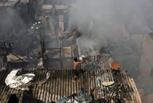 India Prints: A man pours water to douse a fire that broke out in a slum in Mumbai