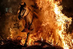 A man rides a horse through flames during the annual Luminarias celebration on the eve