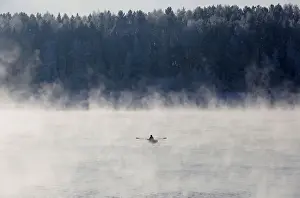 A man rows a boat through a frosty fog along the Yenisei River at air temperature