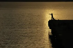 Images Dated 2012 April: A man is silhouetted as he fishes on a pier at Uleelheu port in Banda Aceh