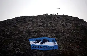 Argentina Prints: A man stands next to a cross as an Argentine national flag with an image of the Falkland