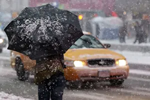 Man stands under a snow-covered umbrella at Times Square in New York