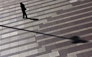 Man talks on mobile phone as he walks on a patterned floor at a yard outside an office