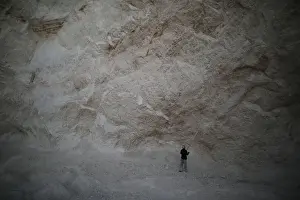 Haiti Prints: A man uses a long stick to hit rocks and get sand in a sand mine on the outskirts of Fond