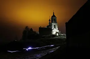 Prints of A man uses a torch as he leaves a church after an Orthodox Easter night mass in the settlement of Roshcha, some 100 km (63 miles) south-west of Moscow, April 4, 2010 Russia Prints: A man uses a torch as he leaves a church after an Orthodox Easter night mass in
