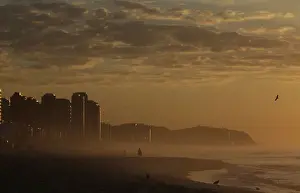 A man walks in Barra da Tijuca beach during the sunrise in Rio de Janeiro
