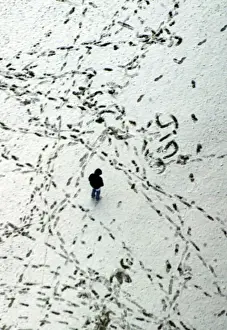 A MAN WALKS AMONG FOOTPRINTS IN THE SNOW COVERED OLYMPIC PARK IN MUNICH
