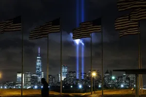Man walks past as the Tribute in Light is illuminated on the skyline of lower Manhattan