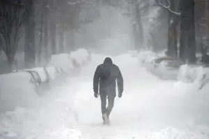 A man walks along a street covered by snow during a winter storm in Washington