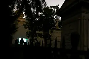 A man watches a movie in a cemetery as part of Ghost Tour heritage circuit, in Santiago