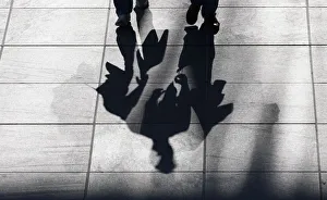 Two men cast their shadows on the street as they carry a shopping bag, in Berlin Two men cast their shadows on the street as they carry a shopping bag, in Berlin