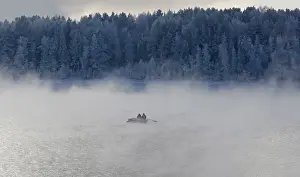 Two men row a boat through a frosty fog along the Yenisei River at air temperature some