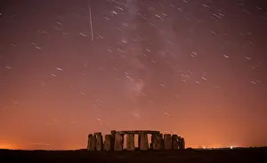 A meteor streaks past stars in the night sky over Stonehenge in Salisbury Plain