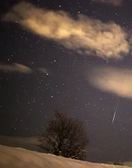 Bosnia Prints: A meteor streaks past stars in the night sky over the village of Pesevici