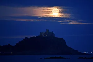 The full moon rises behind St. Michaels Mount in Penzance, Cornwall, Britain