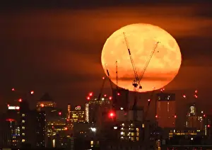 Moonlight Prints: The full moon is seen rising behind skyscrapers at Canary Wharf and the London skyline