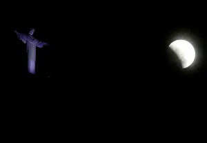The moon is seen next to the statue of Christ the Redeemer during a total lunar eclipse