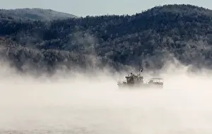 A motorboat travels along the Yenisei River in the Siberian Taiga area as the air